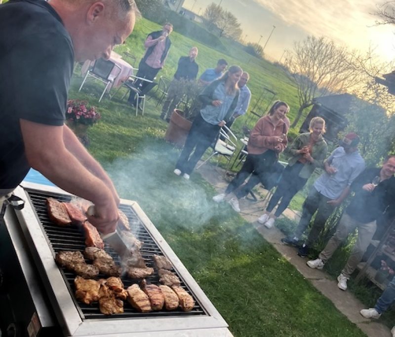 Grillbuffet Luca Metzgerei - Fleisch am Grill und Gäste stehen im Garten